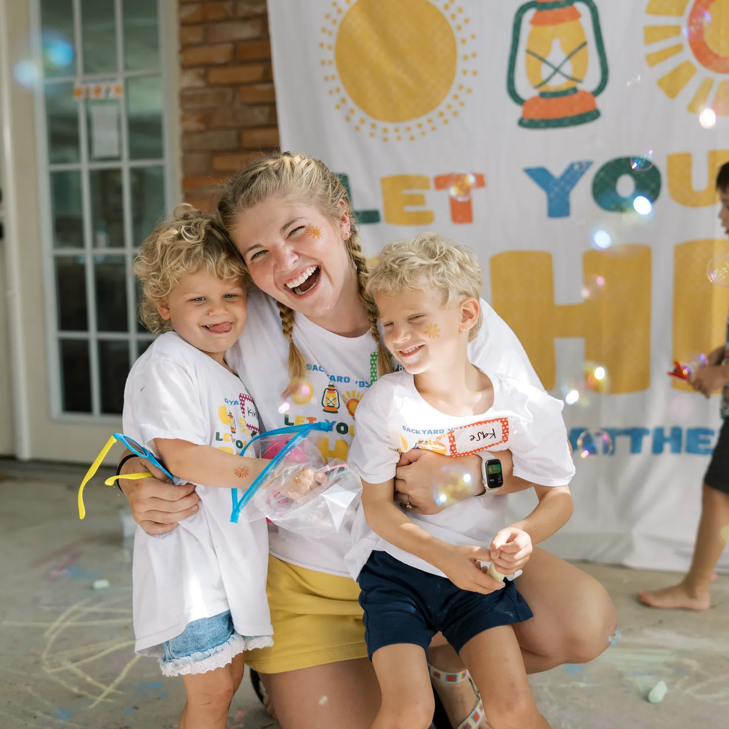 Madison Roberts, founder of Backyard VBS, laughing with two neighborhood kids